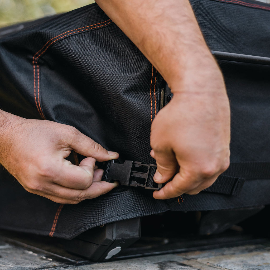 Man uses 2 hands to connect the buckle to cinch cover into place