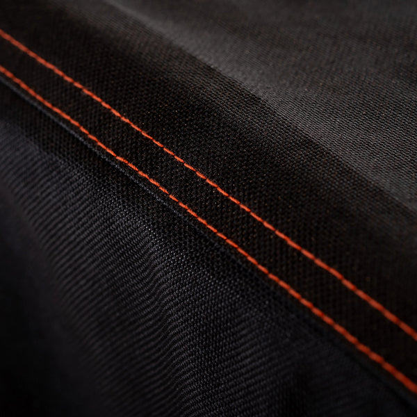 Extreme closeup of a double-stitched seam. The seams are stitched using orange thread so they add accents to the cover.