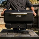 Man lifting a Portable Charcoal BBQ and Smoker with the lid closed and locked